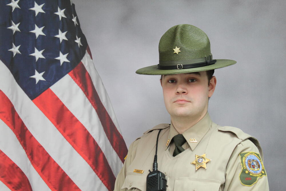 Deputy Austin Beazley pictured in front of an American Flag.