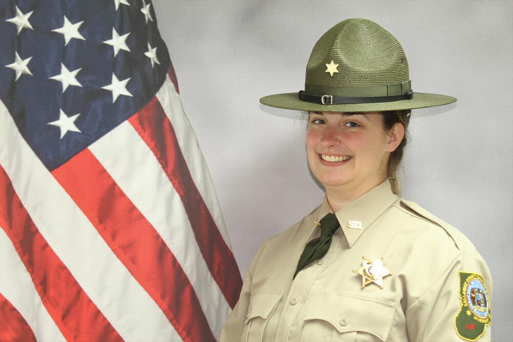 Investigator Caroline Hammond in uniform pictured in front of an American Flag.