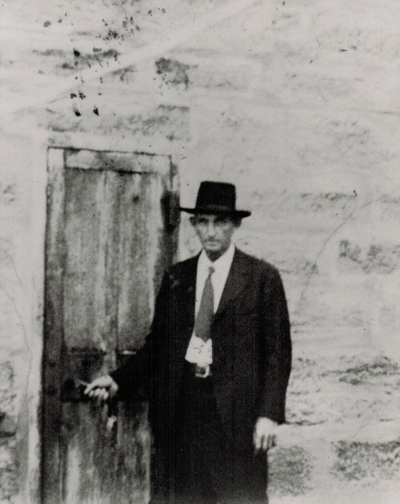 A black and white image of Harris Wells.  Wells is standing by the door to the old stone jail that was once located east of the courthouse. 