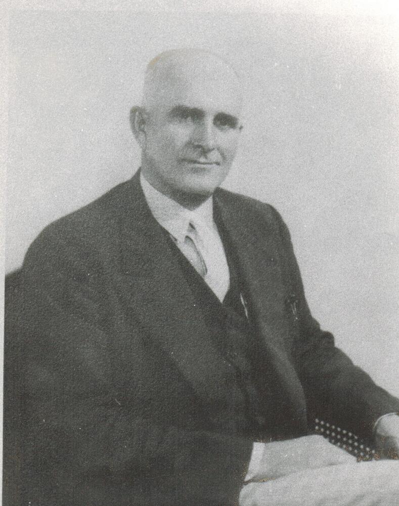 A black and white image of Hartley Crowson.  Crowson is seated and wearing a suit jacket and vest.
