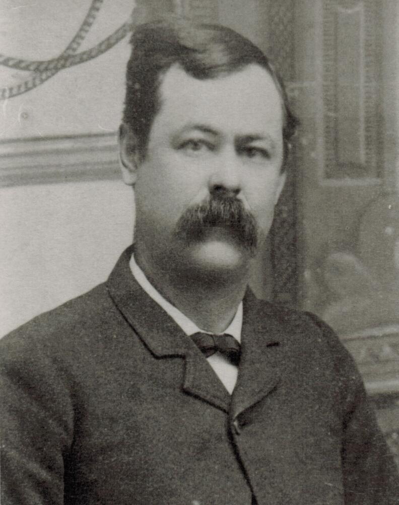 A black and white image of William V. Berry wearing a suit and bowtie.