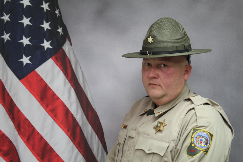 Cpt Robbie Harrison pictured in front of an American Flag.