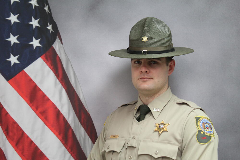 Deputy Zach Carey pictured in front of an American Flag.