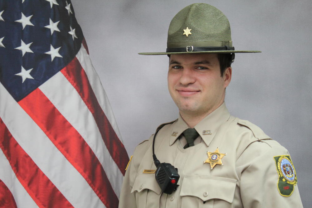Deputy Nicholas Jensen pictured in front of an American Flag.