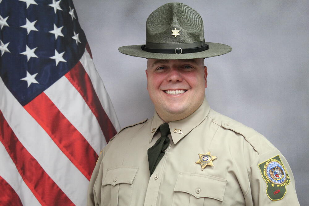 Investigator Ryan Lacey pictured in front of an American Flag.