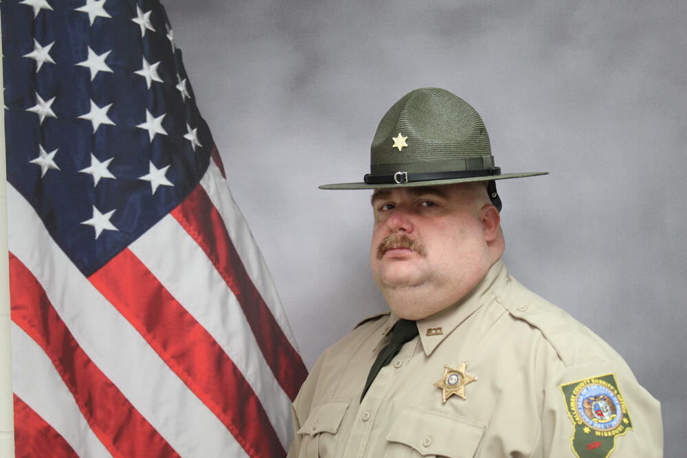 Investigator Ryan Stiffler pictured in front of an American Flag.