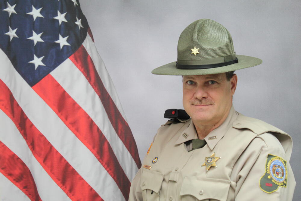 Deputy Jackie Karhoff pictured in front of an American Flag.