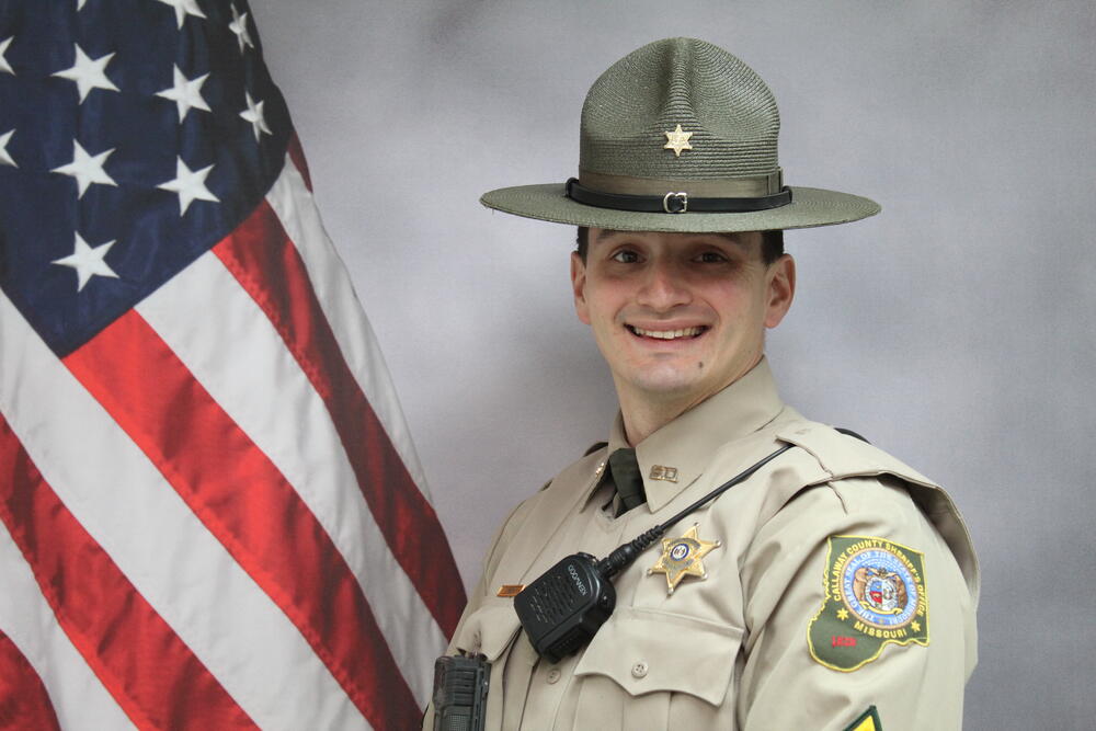Sgt Ryan Smith pictured in front of an American Flag.