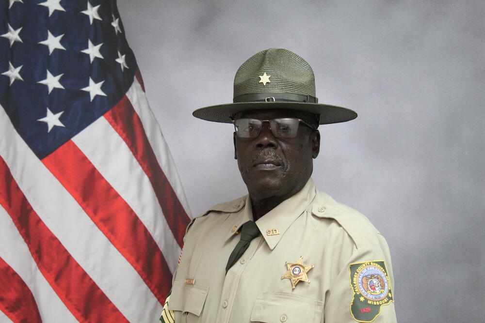Sgt Fred Cave pictured in front of an American Flag.