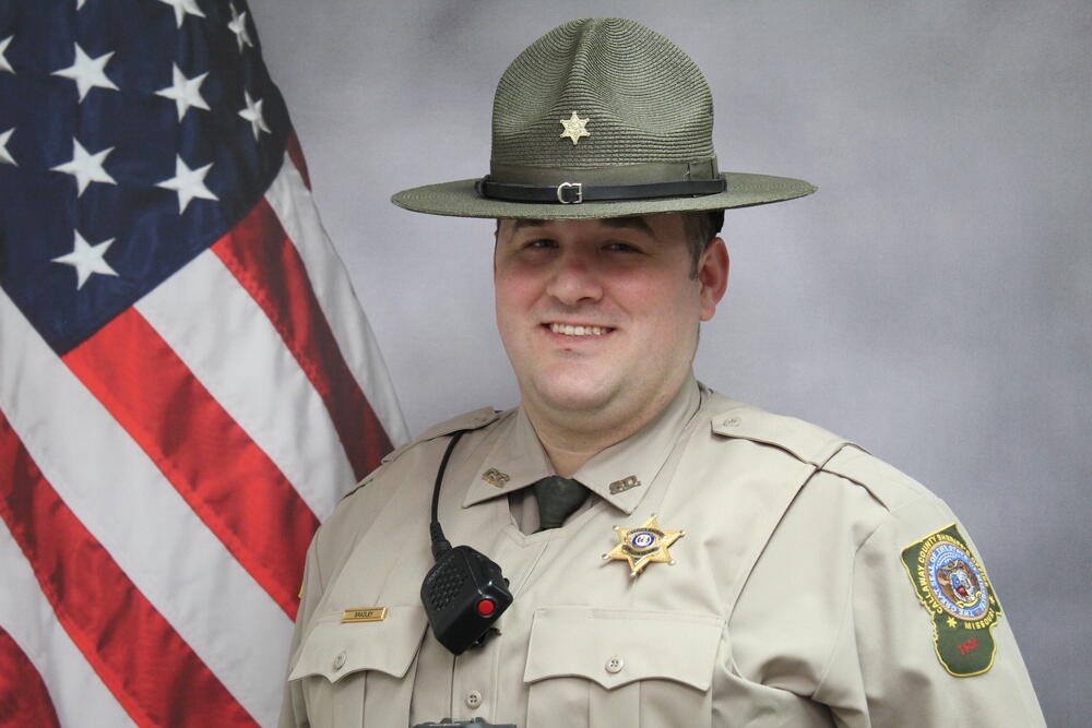 Deputy Jon Bradley pictured in uniform in front of an American Flag..