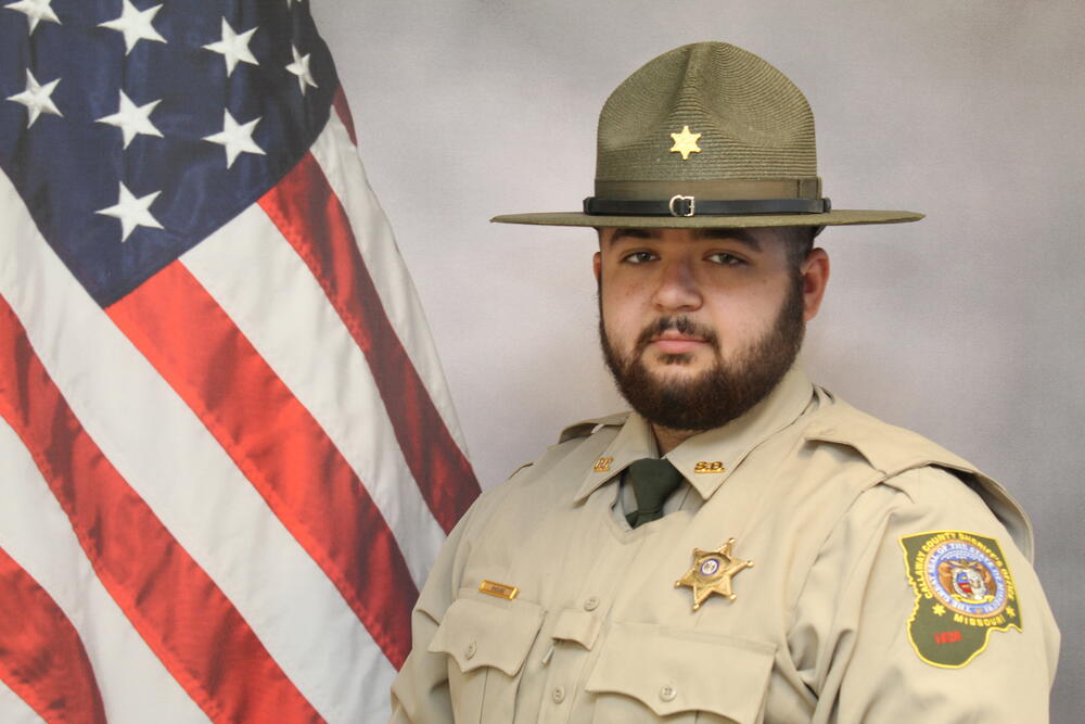 Deputy Keenen Shouse pictured in uniform in front of an American Flag.