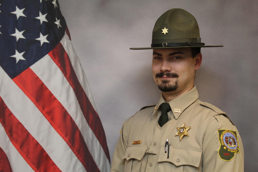 Deputy Dakotah Erny pictured in uniform in front of an American Flag..