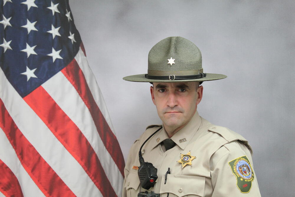 Deputy John Nielsen pictured in uniform in front of an American Flag.